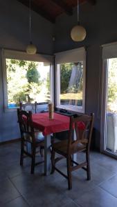 a dining room with a red table and two windows at Casa de montaña in San Carlos de Bariloche