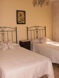1 dormitorio con 2 camas con sábanas blancas y lámpara de araña en Casa Los Olivos, en Grávalos