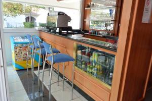 a bar with blue stools and a counter with drinks at Hotel Paris in Lignano Sabbiadoro