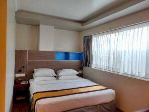 a small bedroom with a bed and a window at Hotel Grand United - Ahlone Branch in Yangon