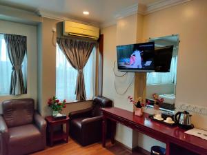 Hotel Grand United - Ahlone Branch في يانغون: غرفة معيشة مع كرسيين وتلفزيون بشاشة مسطحة