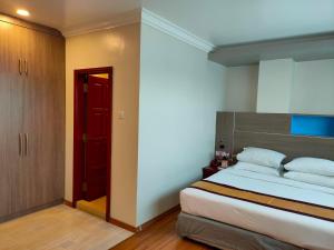 1 dormitorio con 1 cama grande y puerta roja en Hotel Grand United - Ahlone Branch en Yangón