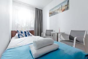 - une chambre avec un lit doté d'une couverture bleue et de chaises dans l'établissement Apartament YAGI z bezpłatnym parkingiem Dziwnówek nad morzem EPapartamenty, à Dziwnówek