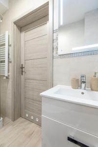 La salle de bains est pourvue d'un lavabo blanc et d'une porte. dans l'établissement Apartament YAGI z bezpłatnym parkingiem Dziwnówek nad morzem EPapartamenty, à Dziwnówek 85 autres photos