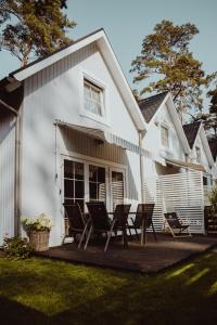 a white house with chairs on a wooden deck at 8 Sosen Pobierowo in Pobierowo