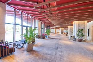 duży korytarz z roślinami w budynku z czerwonymi belkami w obiekcie Okinawa Prince Hotel Ocean View Ginowan w mieście Ginowan