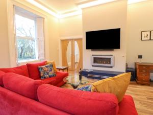 a living room with a red couch and a tv at Glebe House in Seaham
