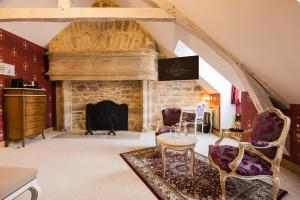 a living room with a stone fireplace and chairs at LE PETIT MANOIR in Sarlat-la-Canéda