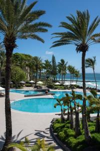 uma piscina com palmeiras e o oceano ao fundo em The Residence Mauritius em Belle Mare