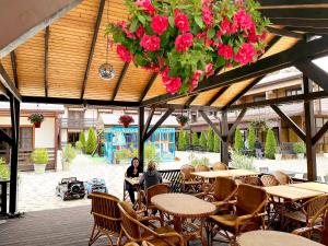 a woman sitting at a table in a patio with flowers at Пляж Отель Терраса in Anapa