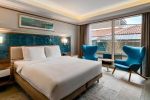 una camera d'albergo con un letto e due sedie blu di Radisson Blu Bosphorus Hotel a Istanbul Altre 37 foto