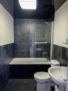 a bathroom with a tub and a toilet and a sink at The New George Hotel in Newcastle upon Tyne
