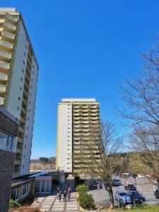 un edificio blanco alto con gente caminando delante de él en Appartement zum Kuckuck noch mal, en Hohegeiss