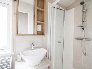 Un baño con lavabo blanco y ducha. en Denbigh 8, en Borth 19 fotos más