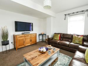 a living room with a couch and a tv at Lower Butchers Cottage in Weymouth