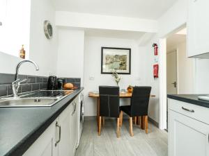 a kitchen with a sink and a table with chairs at Lower Butchers Cottage in Weymouth