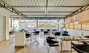 een restaurant met tafels en stoelen en een groot raam bij Treebo Trend Sai Village Gold Souk - Sec 43 in Gurgaon