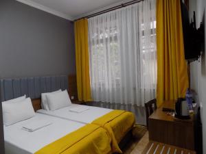 a bedroom with two beds and a window with yellow curtains at Palm Hotel in Batumi