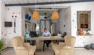 a man sitting at a table with a computer at CHARM BEACH HOTEL in Akyarlar