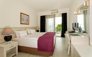 a bedroom with a bed and a desk and a sink at CHARM BEACH HOTEL in Akyarlar