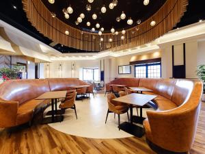 a restaurant with brown leather seats and tables at ORIENTAL HOTEL UNIVERSAL CITY in Osaka