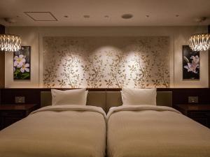 Okinawa EXES Naha في ناها: سريرين في غرفة الفندق مع وسادتين