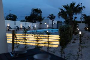 una piscina con sillas y una valla por la noche en MrBrown - Cinzia Resort Beach, en Mazara del Vallo