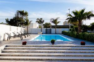 a swimming pool with stairs and chairs next to a building at MrBrown - Cinzia Resort Beach in Mazara del Vallo