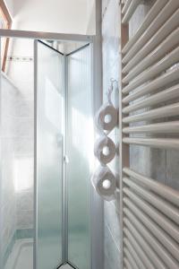 un bagno con porta doccia in vetro e termoarredo. di LA CASA DI LAZISE a Lazise