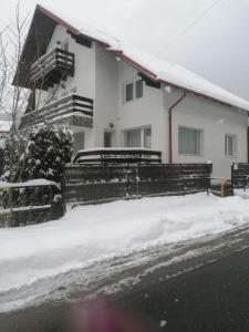 a house with a fence in the snow at MIRAJ in Azuga