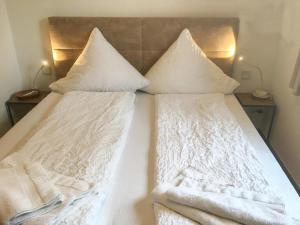 Una cama con sábanas blancas y almohadas. en Ferienwohnung Sonnendüne Insel Juist, en Juist