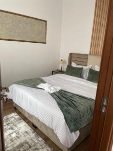 een slaapkamer met een bed met witte lakens en groene kussens bij Norderney Apartments in Sibiu