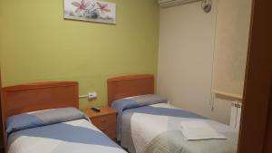 2 camas en una habitación con paredes verdes en Hostal Los Amigos, en La Roda
