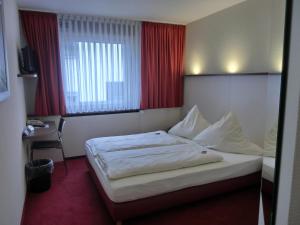 a hotel room with a bed and a desk and window at Central Hotel Garni in Würzburg
