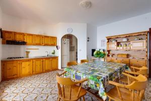 una cocina con mesa y sillas y una cocina con armarios de madera. en La Terrazza sul Mare, en Magomadas