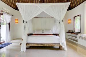 a bedroom with a bed with a canopy at Rumah Kelapa Sepi in Karangasem