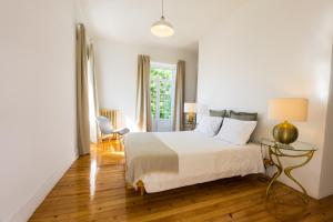 a white bedroom with a bed and a window at 3 Marias Residence in Viana do Castelo