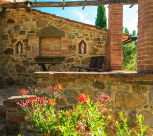 eine Außenterrasse mit einer Steinmauer und Blumen in der Unterkunft Piccolo Borgo Gagnoni in Sinalunga