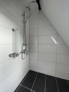 La salle de bains est pourvue d'une douche et de carrelage blanc. dans l'établissement Zentral gelegenes Apartment am Bunter Garten, à Mönchengladbach