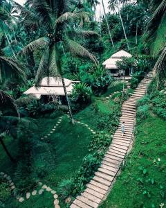 a person walking down a path through a palm tree at Galalima Glamping in Tabanan