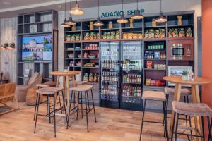 a restaurant with stools in front of a refrigerator at Adagio Access Stuttgart Airport Messe in Leinfelden-Echterdingen