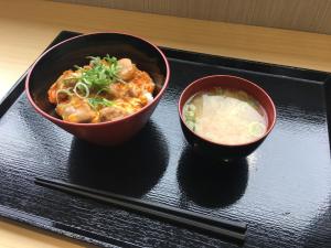 twee kommen eten op een zwart dienblad met eetstokjes bij Y's HOTEL Hanshin Amagasaki Ekimae in Amagasaki