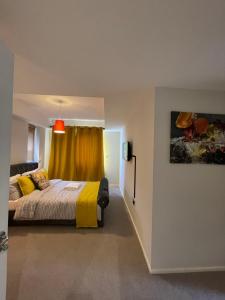 a bedroom with a bed with a yellow curtain at The Reflection Apartment , With river Thames view in North Woolwich