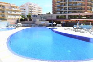 a large swimming pool with chairs and a building at OÁSIS Beach Apartment in Portimão