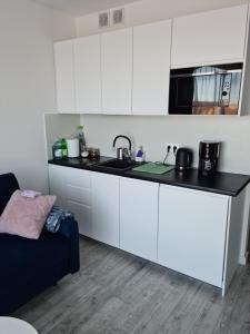 a kitchen with white cabinets and a black counter top at COSTA Apartamenty w Sarbinowie in Sarbinowo