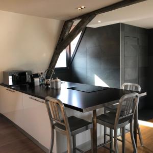 a kitchen with a black counter and two chairs at DUPLEX 15 in Colmar