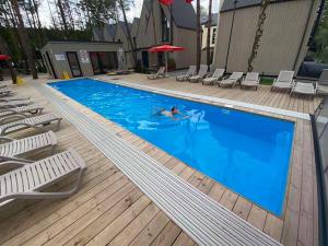 a person swimming in a swimming pool with chairs at Sun&Sea in Palanga