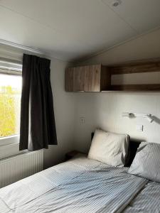 een kleine slaapkamer met een bed en een raam bij Polderhuisje 2 - Heerlijk chalet met overkapt terras en 2 slaapkamers - max 4 pers - 3 km van Noordzee - locatie op camping 2 in Rockanje