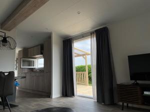 a living room with a sliding glass door to a deck at Polderhuisje 2 - Heerlijk chalet nabij strand en duin - 2 slaapkamers - Midicamping - Rockanje in Rockanje