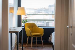 a yellow chair sitting in a room with a window at Amazing Via Parigi in Rome